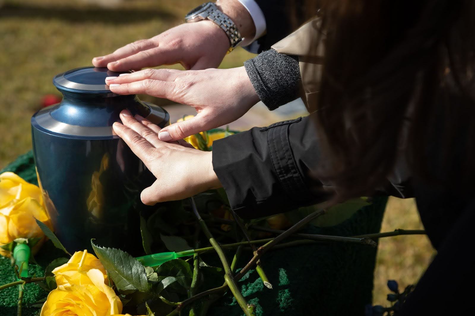 Hands touching cremation urn at funeral