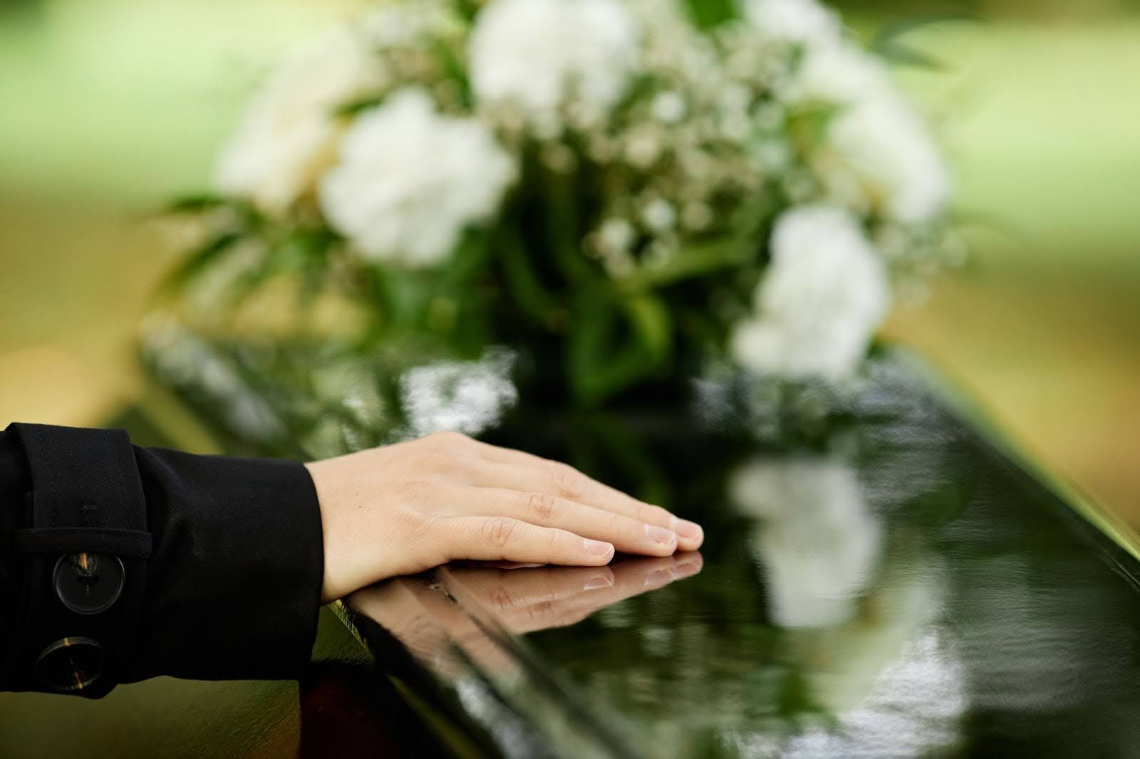 Hand pictured on coffin saying goodbye at funeral ceremony