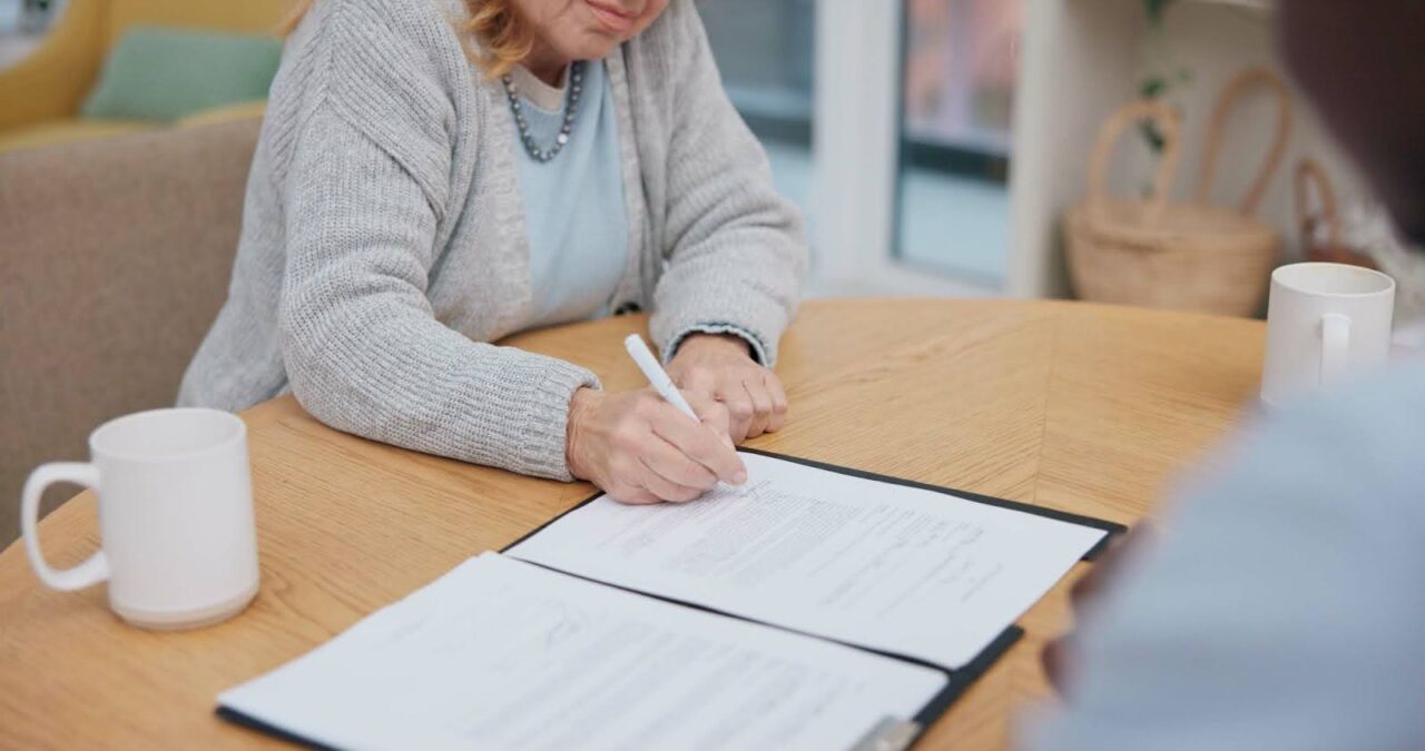 Senior woman signing end-of-life documents with lawyer