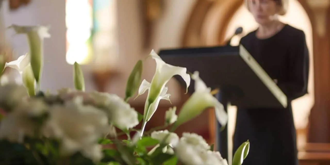 Woman delivering speech at funeral with flowers in foreground