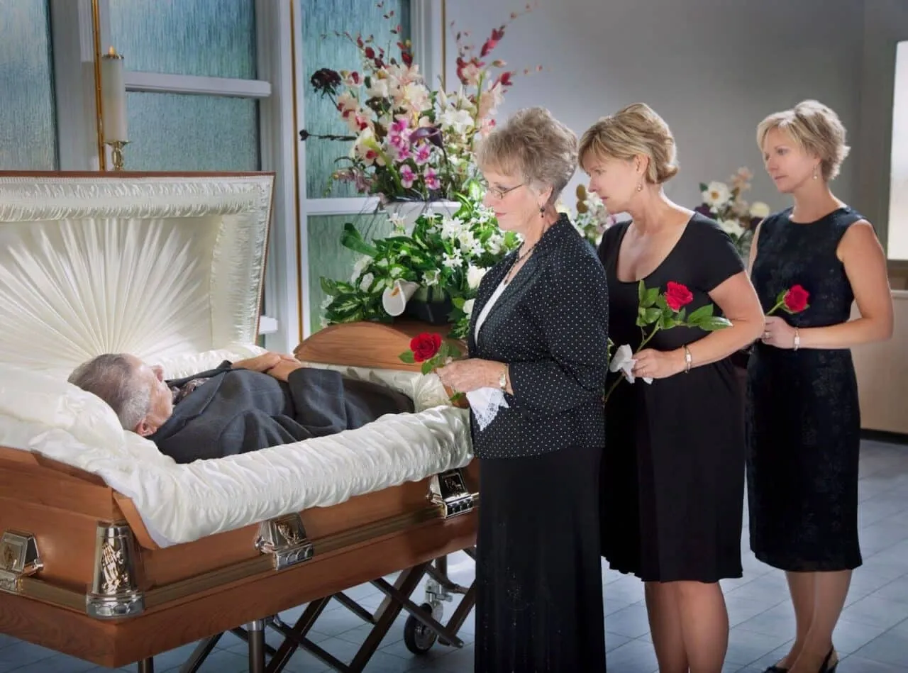 Three women viewing and mourning a loved one at open casket funeral