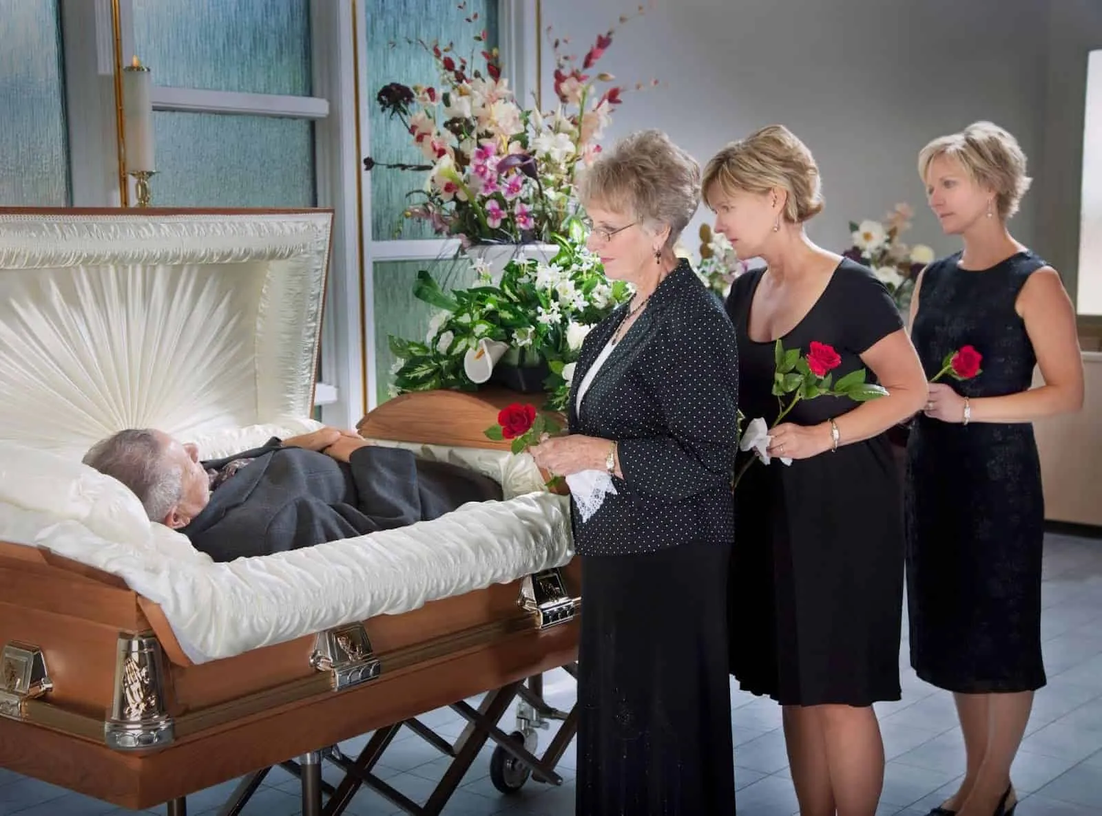 Three women viewing and mourning a loved one at open casket funeral