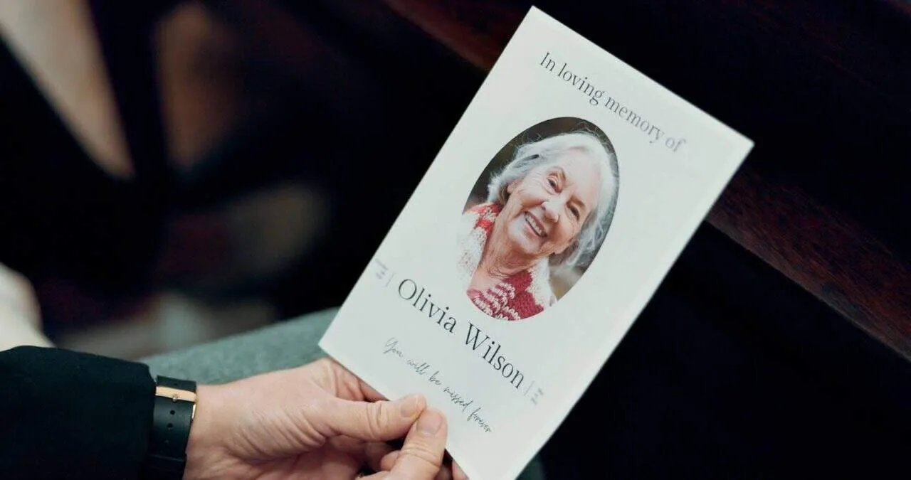 Hands holding obituary at funeral