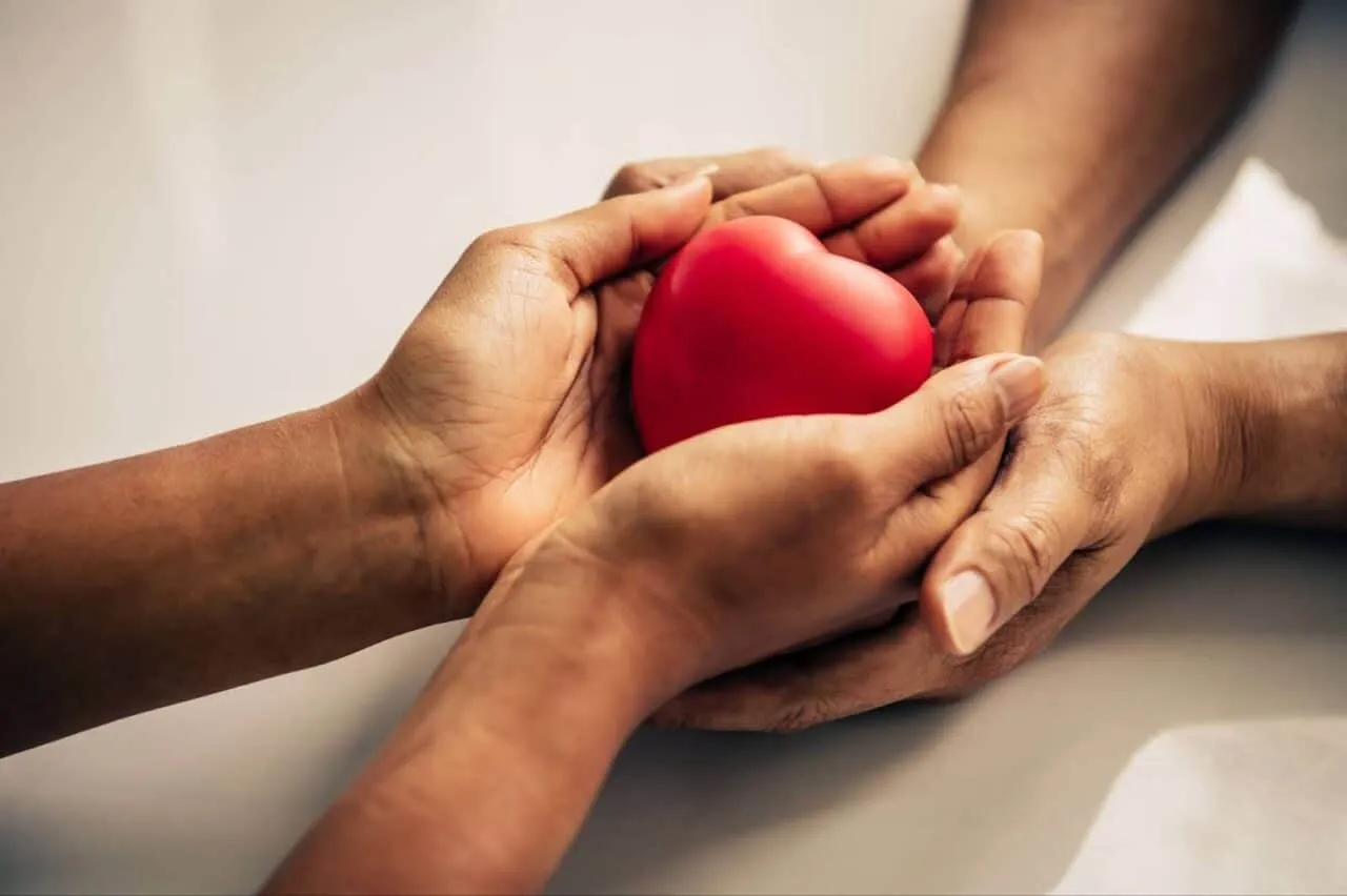 Two pairs of hands, passing heart from one person to other, symbolizing organ donation
