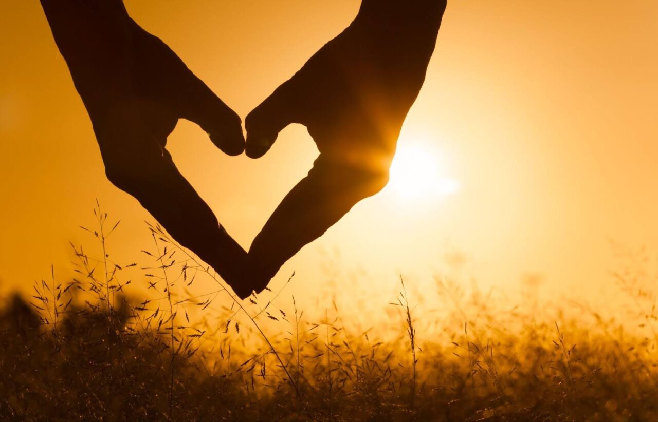 Hands forming heart shape against sunset sky, symbolizing generosity and body donation